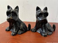 Front angled view of both cast-iron Scotty dog bookends on a wooden surface showing overall condition and details
