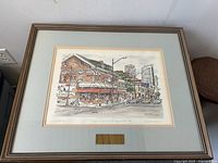 Framed hand-coloured art print shows Dempster's Hardware building at the corner of Yonge and Sheppard St with street scene and distant buildings, signed by Lynette Yu.