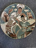 Top view of large circular glazed pottery charger with two women depicted in Ukrainian folklore style, detailed hand-painted design in multiple colors.