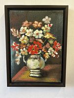 Straight-on view of the framed oil painting depicting a lush floral bouquet in a vase on a table, signed by artist Vicky.