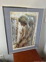 Framed serigraph print showing nude female figure standing in profile with mirror reflection, light reflecting on glass, hung or resting against a wall