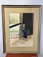 Framed watercolor painting of a barefoot child in a barn, signed KA, showing the child standing in the doorway holding the barn door with light highlighting the figure.