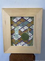 Photo showing the full framed acrylic painting with surreal imagery of a girl and a large round object on a decorative patterned floor.