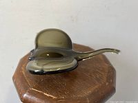Single art glass stingray figurine sitting on a wooden octagonal surface showing top view.