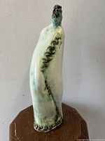 Front view of the hand-sculpted statue showing detailed textured spine and glazed turquoise finish.