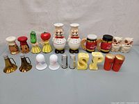 A front view showing 10 vintage salt and pepper shakers in various colorful and novelty designs including owls, chefs, vegetables, jars, letters S and P, and metal shakers.