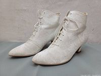 Pair of white satin brocade ankle boots with lace-up fronts and pointed toes.