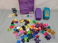 Overview of assorted colorful plastic Gogo's Crazy Bones figurines scattered on table with two small boxes and a booklet overlapped behind them