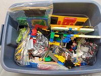 Wide view of plastic storage bin filled with assorted LEGO bricks and baseplates.