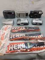 Six cameras including Hewlett Packard 1 megapixel and Kodak, along with three new camera straps in packaging.