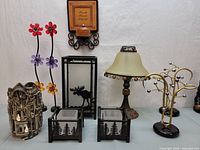 Various home decor iron candle holders displayed on white surface with different designs including nature themes and floral wire accents