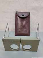 Front view of leather case with embossed brand and model text standing behind the glasses