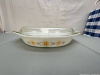 Side view of the Pyrex dish showing the opaque white glass with Town and Country orange flower pattern.