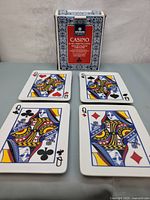 Four ceramic plates displayed along with original box showing the Queen playing card designs on each plate: Hearts, Spades, Clubs, Diamonds.