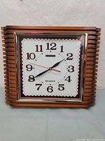 Full front view of the vintage Ginga quartz wall clock showing wooden frame and clock face.