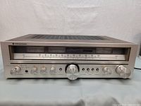 Front view of receiver showing silver faceplate, central tuning knob, VU meters and control knobs