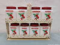 Front view of the full spice shaker set in the metal rack showing all labeled spice containers.