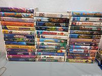 Front view of stacked VHS tapes showing titles on spines including Disney and kids movies.