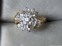 Top down view showing cluster of clear cubic zirconia stones in a floral arrangement on a gold toned band.