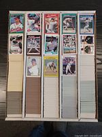Front-facing photograph showing multiple baseball cards from various manufacturers arranged in five long vertical stacks in display boxes. The cards include images of players in different actions with colorful card fronts and some visible player names.