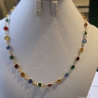Front view of the 16-inch necklace with colorful round stones on gold-tone metal links displayed on a white necklace stand.