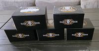 Five black boxes of Hair Pride Pomade stacked on a table.