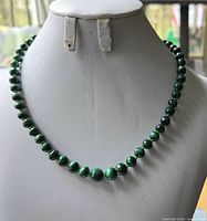 Front view of malachite bead necklace on white display bust showing full length and graduated bead sizes.