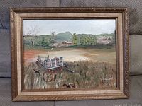 Overall view of vintage framed landscape painting showing rural scene with a cart and farm buildings.