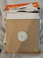 Stack of assorted records including one in a plain brown 'Hoop Choons' sleeve with a logo in the center