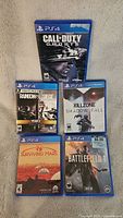 Photo of 5 PlayStation 4 game cases showing cover art for Call of Duty Ghosts, Tom Clancy Rainbow Six Siege Year 2, Killzone Shadow Fall, Surviving Mars, and Battlefield 1.