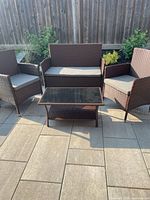 Full view of two chairs, loveseat and coffee table arranged on stone patio