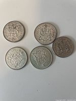 Top view of 5 Canadian 50 cent coins showing the Coat of Arms design.