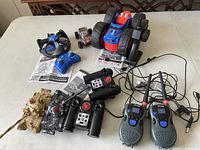 Photo showing two remote control tanks, a drone, two different remote controllers, charging cables and manuals laid out on a table.