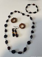 Full set of Baltic amber jewelry on white background including necklace, bracelet, earrings, and two rings arranged flat