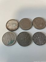 Six different Canadian commemorative coins arranged on a surface showing various designs and degrees of wear.