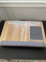 Top view of the lap desk showing wood surface with device slots, mouse pad area, and cushioned wrist support.