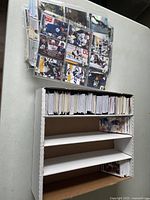 Wide shot of a cardboard box filled with many sports trading cards, with some cards laid out above it.