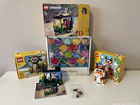 Photo showing LEGO Creator set 40491 Tiger missing tail, set 40417 sealed in open box, set 40469 with built model and extra pieces, and Paint Party 1000-piece puzzle box