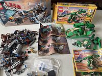 Photo of opened LEGO Movie 70806 Castle Cavalry pieces, instruction manuals, and LEGO Creator 31058 Mighty Dinosaurs box and build pieces on a white surface.
