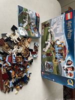 Overall set view showing disassembled pieces, instruction manual, and box for LEGO Harry Potter 75958 stagecoach carriage with white Pegasus figures.
