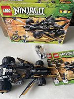 Front view of the LEGO Ninjago Set 9444 box with built black and orange flying vehicle, instruction booklets, and minifigures in plastic bags.