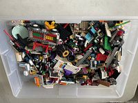 Overhead view of transparent container filled with assorted LEGO pieces in multiple colors and shapes.