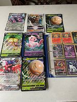 Six featured holofoil cards displayed outside binder: Oinkologne EX, Kleavor VSTAR, Alolan Exeggutor V, Mew V, Koraidon EX, Hisuian Electrode V