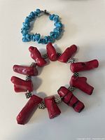 Photo showing red coral nugget bracelet and blue turquoise chip bracelet laid flat, clear view of materials and clasp.