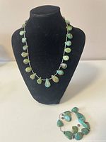 Necklace and bracelet displayed on a black jewelry bust. Necklace made of natural Chinese turquoise nugget beads with silver-tone spacer beads. Bracelet is stretch with loose turquoise beads.