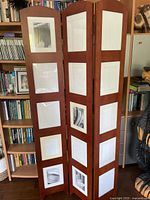 Front view of the three-panel brown wood room divider with integrated photo frames showing overall structure and panel design.