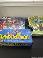 Three board games on table: Scooby-Doo Clue, LEGO Constructionary, Sneaky Snacky Squirrel tree-shaped box.