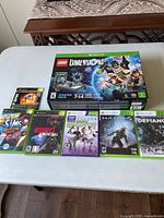 Photo showing LEGO Dimensions Starter Pack with 269 pieces box and six Xbox/Xbox 360 game cases on a table