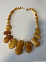 Front view of the necklace showing a series of irregular yellow amber slab beads mixed with smaller rounded beads. The beads have natural color variations and some inclusions. The strand is open at the end missing a clasp.