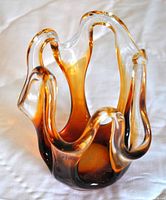 Angled front view showcasing the amber gradient and the wavy open work edges of the glass sculpture.